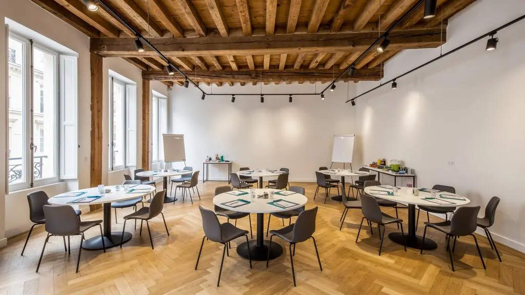 Espace événementiel parisien modulable configuré pour accueillir des activités de team building avec tables collaboratives et architecture typique